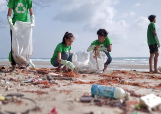 Volunteerism :Group of happy volunteers with garbage bags cleaning area on the beach.Volunteerism,charity, cleaning, people and ecology concept